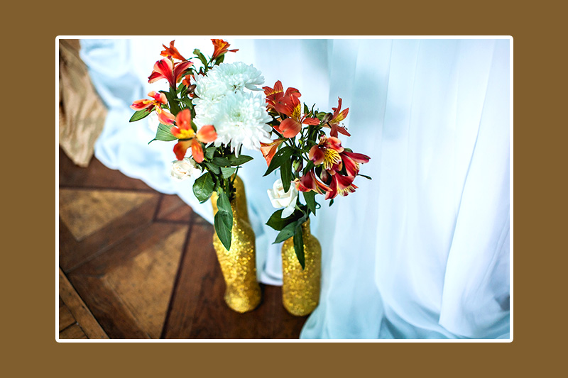 Blumendeko in goldenen Vasen und Flaschen